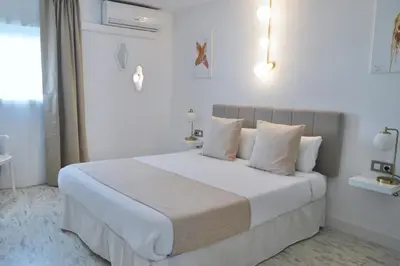 a white bedroom with a large white bed with pillows at Aldara Sitges in Sitges