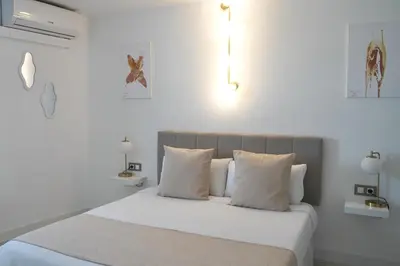 a white bedroom with a bed with white sheets and pillows at Aldara Sitges in Sitges