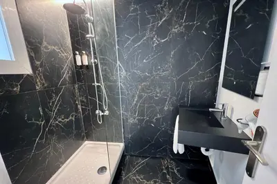 a bathroom with a shower and a black marble wall at Aldara Sitges in Sitges