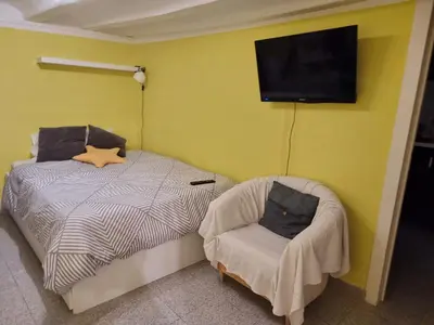a bedroom with a bed and a chair and a flat screen tv at Cozy Apartment downtown BCN, AC, 30 nigths min in Barcelona