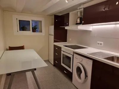 a kitchen with a table and a washing machine at Cozy Apartment downtown BCN, AC, 30 nigths min in Barcelona