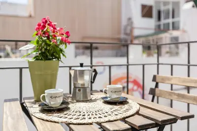a table with two coffee cups and a vase with flowers at Nova Apartment by Hello Homes Sitges in Sitges