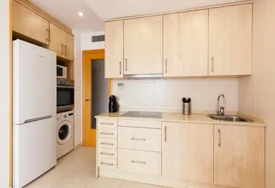 a kitchen with wooden cabinets and a white refrigerator at SOUL by Hello Homes Sitges in Sitges