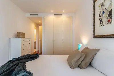 a bedroom with a white bed and a picture on the wall at Canela Homes BARCELONA DIAGONAL MAR in Barcelona