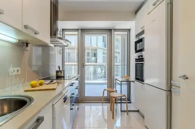 a kitchen with white appliances and a large window at Canela Homes BARCELONA DIAGONAL MAR in Barcelona