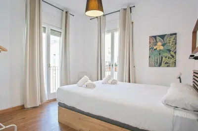 a white bedroom with a large bed and a window at Heaven With a Garden at Las Ramblas in Barcelona