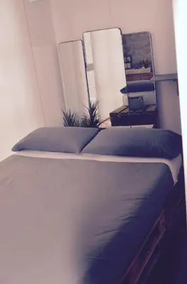 a bedroom with a bed with blue sheets and a mirror at CasaOller in Manresa