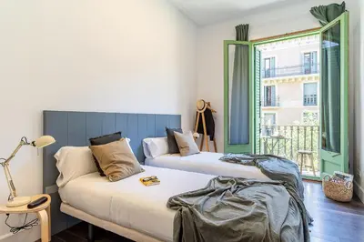 two beds in a room with a couch and a window at Canela Homes BARCELONA FAMILY in Barcelona