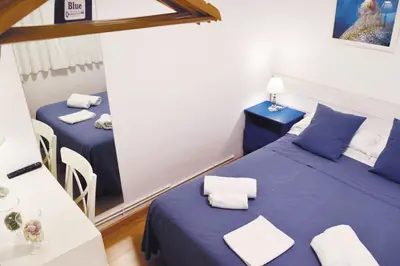 a room with two beds with blue sheets and a table at Blue Barcelona in Barcelona