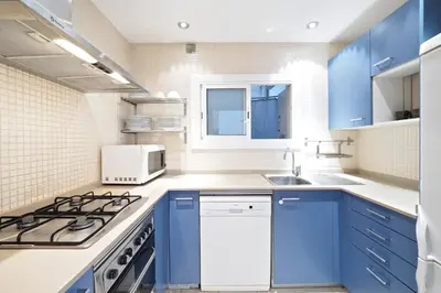 a kitchen with blue cabinets and a stove top oven at Suites Barcelona Park Güell in Barcelona
