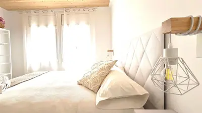 a bedroom with a bed with white sheets and a window at Centro con terraza blco by Prestigi in Terrassa