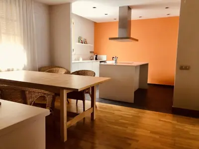 a kitchen with a table and chairs and a kitchen with orange walls at Sant Guillem in Vilassar de Mar