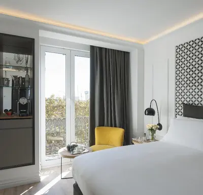 a white bedroom with a large bed and a yellow chair at Serras Barcelona in Barcelona