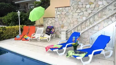 a group of chairs and an umbrella next to a pool at Villa Antonia in Mataró