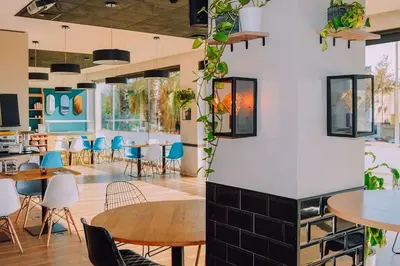 a dining room with tables and chairs and plants at Travelodge BCN Cornella Fira in Cornellà de Llobregat