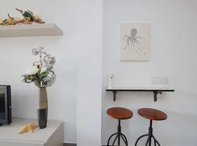 a room with two stools and a vase with flowers at Cel i Mar Canet in Canet de Mar
