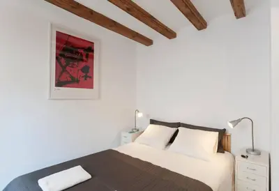 a bedroom with a bed with white walls and wooden ceilings at Central Verdete in Barcelona