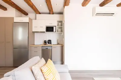 a living room with a couch and a kitchen at Decô Apartments Barcelona-Sants in Barcelona