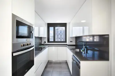 a white kitchen with a sink and a microwave at Seaside Badalona Apartment in Badalona