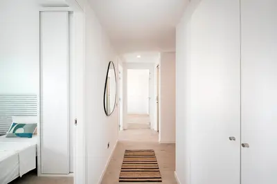 a white hallway with a bed and a rug at Seaside Badalona Apartment in Badalona