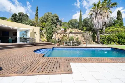 a house with a swimming pool and a wooden deck at Casa Mar Blava con piscina comunitaria junto Barcelona Centro in Alella