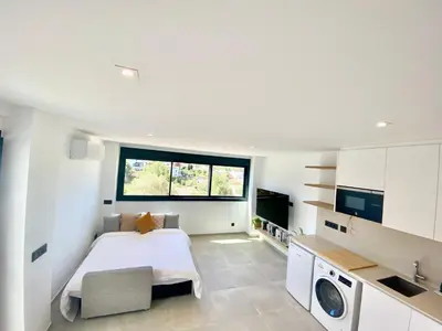 a white bedroom with a bed and a window at Pandi's Place in Sant Pere de Ribes
