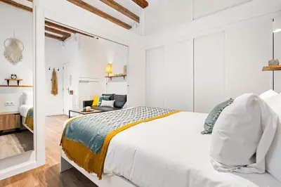 a white bedroom with a bed and a living room at Lodging Apartments Almirall Beach 11 in Barcelona