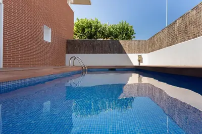 a swimming pool in front of a brick building at Villa Beach Barcelona in Montgat