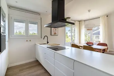 a white kitchen with a sink and a table at Vista Serena in Sant Cugat del Vallès