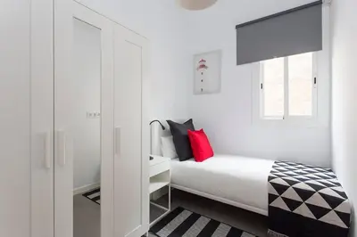 a white bedroom with a bed and a window at Cozy And Quiet In Trendy Sants in Barcelona