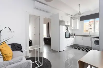 a white living room with a couch and a kitchen at Cozy And Quiet In Trendy Sants in Barcelona