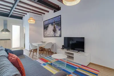 a living room with a couch and a tv and a table at Live Like A Local In Eixample in Barcelona