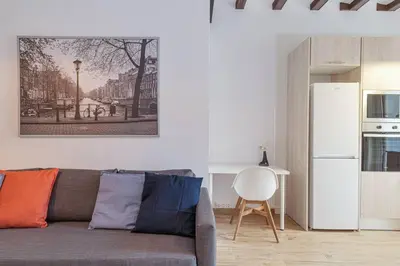 a living room with a gray couch and a white refrigerator at Live Like A Local In Eixample in Barcelona
