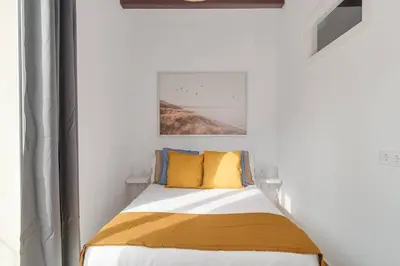 a white bedroom with a bed with yellow pillows at Live Like A Local In Eixample in Barcelona