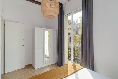 a bedroom with white walls and a large window at Live Like A Local In Eixample in Barcelona