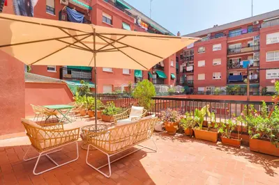 a patio with an umbrella and chairs and potted plants at Amazing Terrace In Sant Andreu in Barcelona