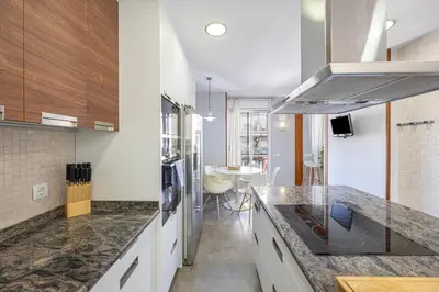 a kitchen with marble counter tops and a dining room at Bright Attic & Amazing Terrace in Hospitalet de Llobregat