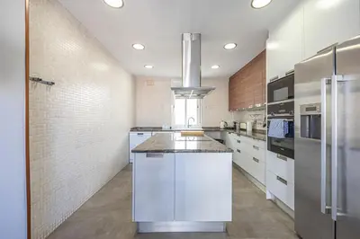 a large kitchen with white cabinets and a refrigerator at Bright Attic & Amazing Terrace in Hospitalet de Llobregat