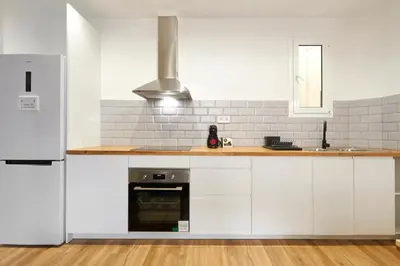 a kitchen with white cabinets and a refrigerator at Comfortable apartment next to Apolo theater in Barcelona