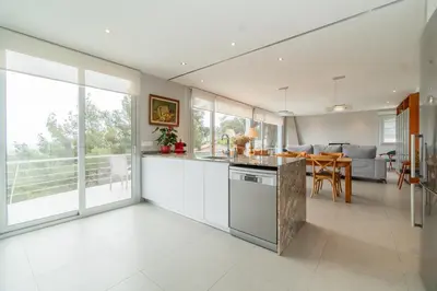 a kitchen with white cabinets and a table and a couch at Casa Majestic in Cunit