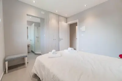 a white bedroom with a bed and a chair at Casa Majestic in Cunit