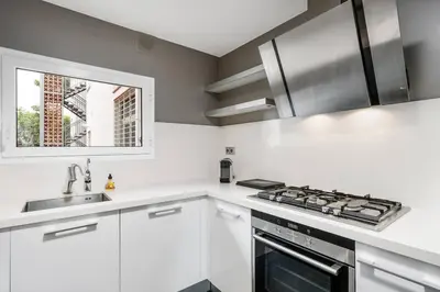 a white kitchen with a stove and a sink at Beachside Bliss in Castelldefels