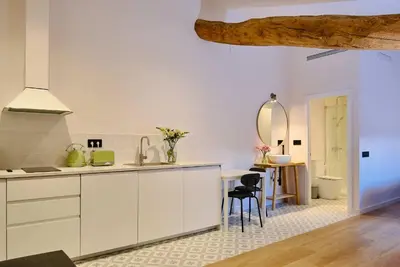 a kitchen with white cabinets and a table and a mirror at Hotel Molí Cardedeu in Cardedeu