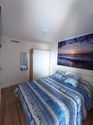 a bedroom with a large bed with a painting on the wall at Apartamento nuevo en Calella totalmente reformado con Parking privado in Calella