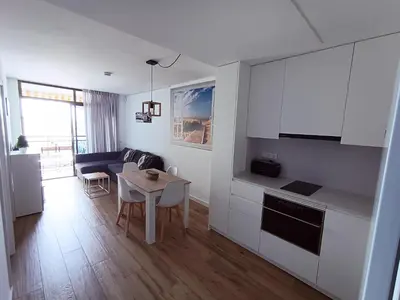 a kitchen and a living room with a table at Apartamento nuevo en Calella totalmente reformado con Parking privado in Calella