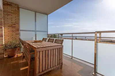 a balcony with a wooden table and chairs at Sunset oceanfront in Castelldefels