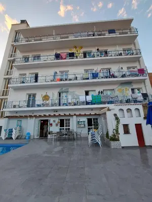 a large building with chairs and tables in front of it at Hotel Mediterrani Express in Calella