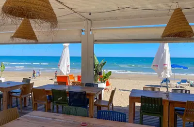 a beach with tables and chairs and the ocean at Apartment Marina in Vilanova i la Geltrú