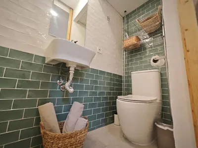 a bathroom with a toilet and green subway tiles at Antic Manresa Atico in Manresa