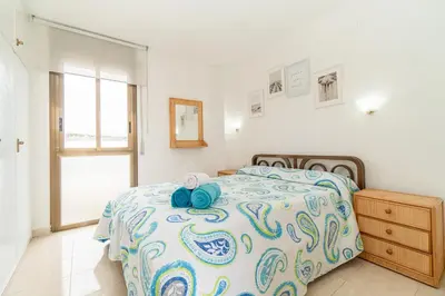 a bedroom with a bed with a blue and white comforter at Apartamento Acqua Fresca in Cunit